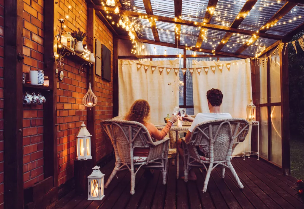 Young couple man and woman sit on white rattan garden chairs on