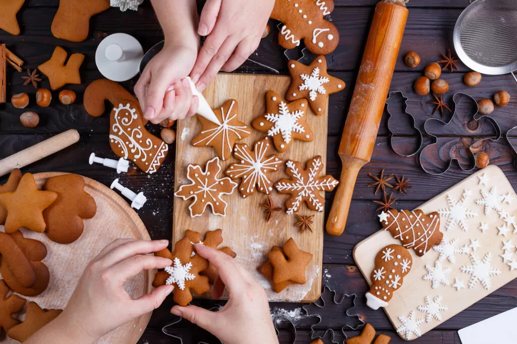 Christmas bakery. Friends decorating freshly baked gingerbread c