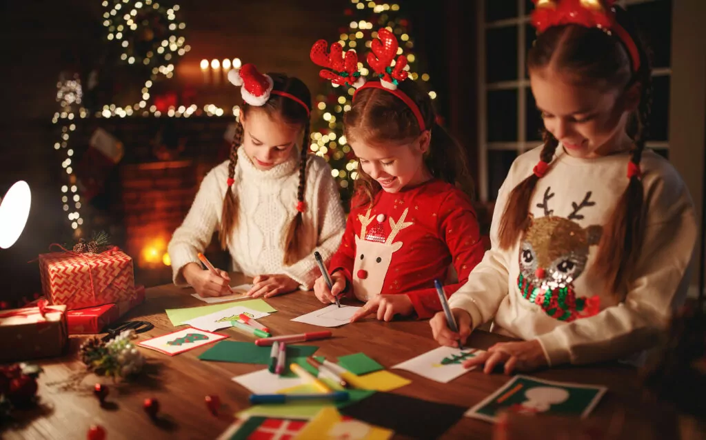 happy friends kids draw decorations and write a letter to Santa near the Christmas tree