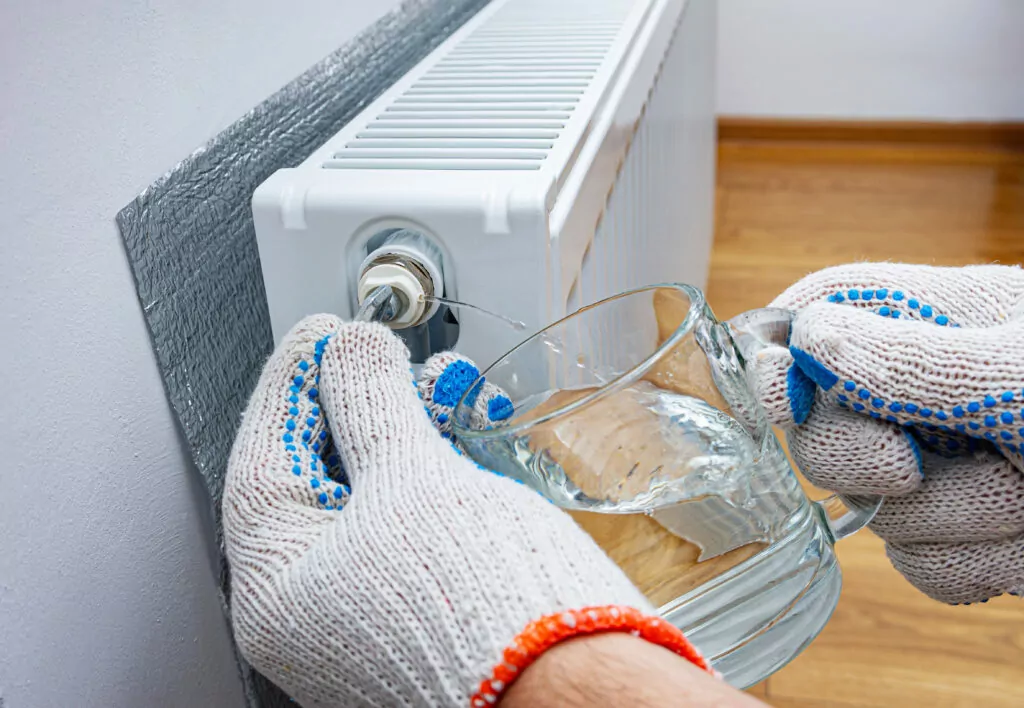 Bleed valve in heating radiator. Hand with a key for draining ai